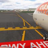 Ein Verkehrsflugzeug wartet an einer Halteposition mit der Aufschrift Cross RWY