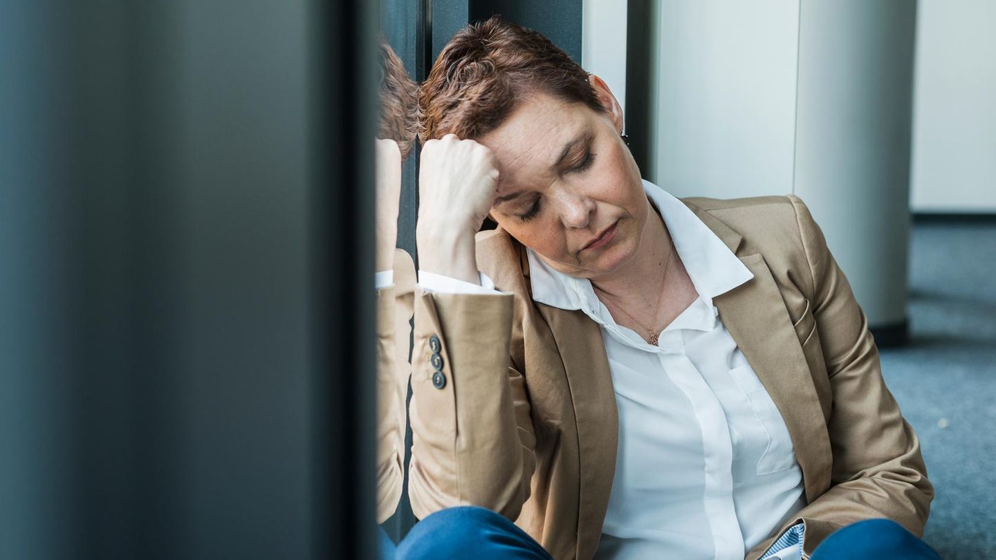 Thema Alkohol im Büro: Erschöpfte Frau sitzt auf dem Boden