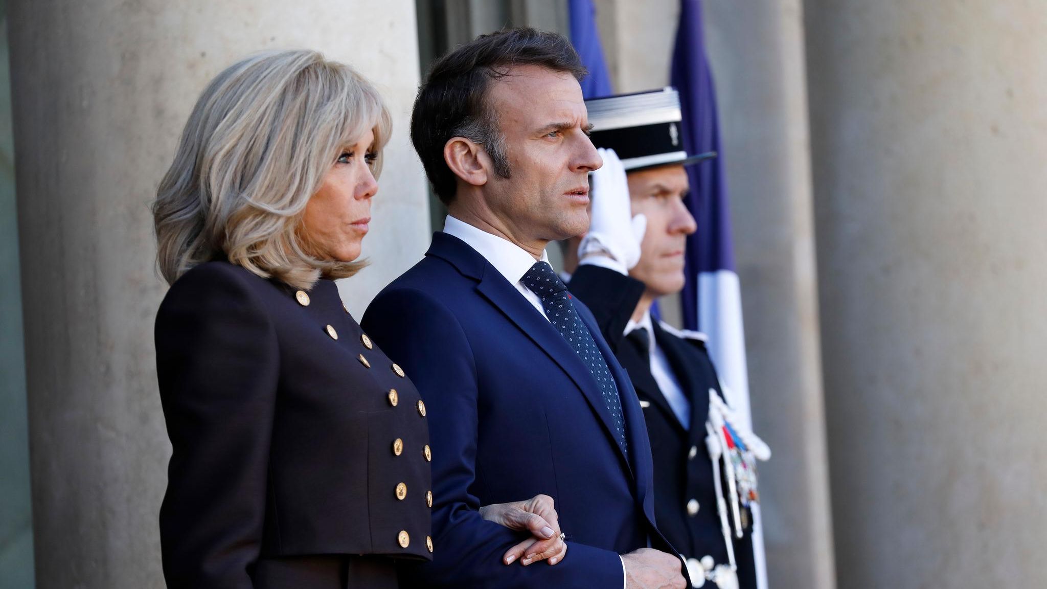 Brigitte Macron steht neben ihrem Mann
