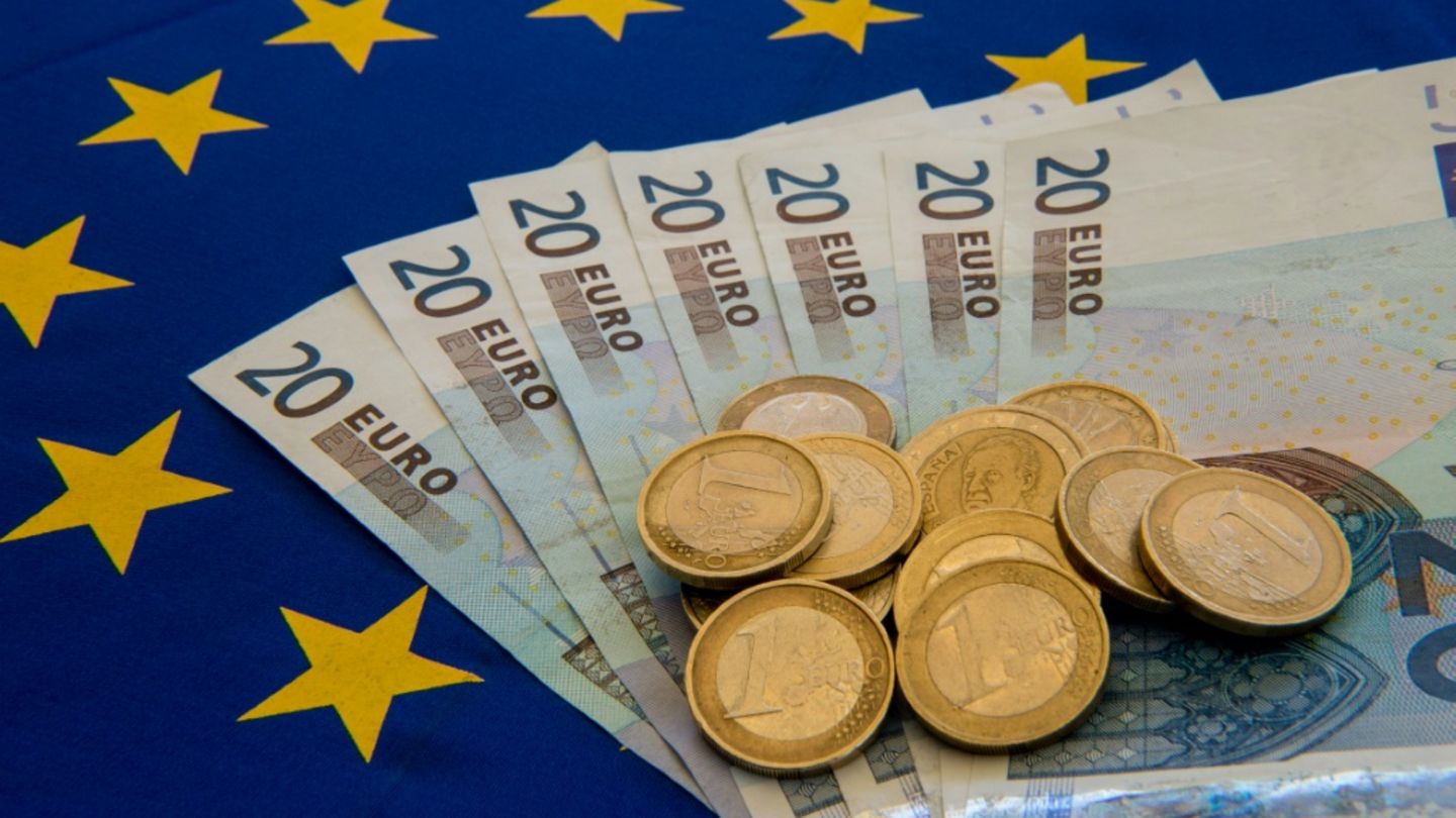 Euromünzen und -scheine auf einer EU-Flagge