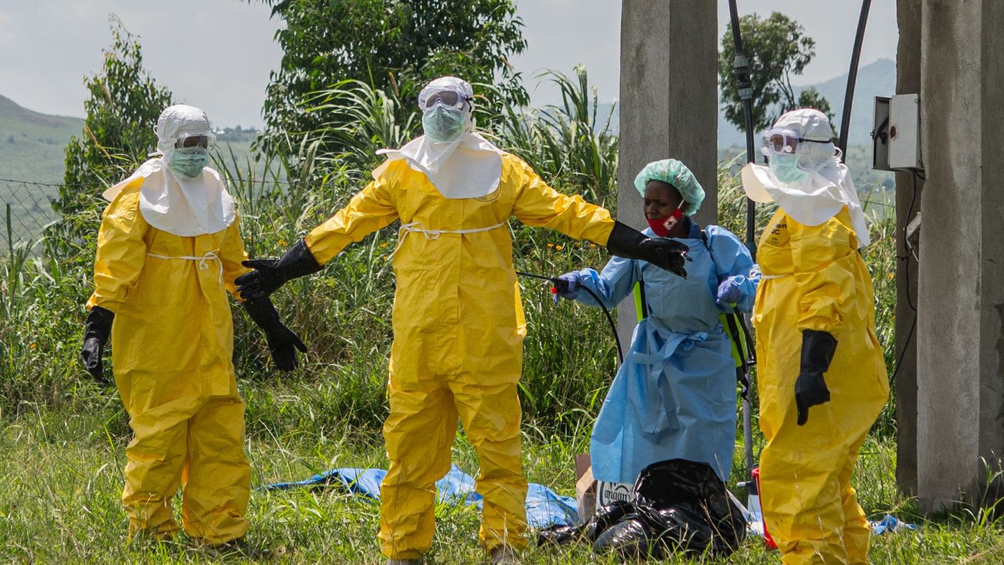 Mitarbeiter des Roten Kreuzes in Schutzkleidung desinfizieren sich. Foto: Moses Sawasawa/AP/dpa