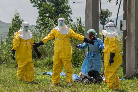 Mitarbeiter des Roten Kreuzes in Schutzkleidung desinfizieren sich. Foto: Moses Sawasawa/AP/dpa