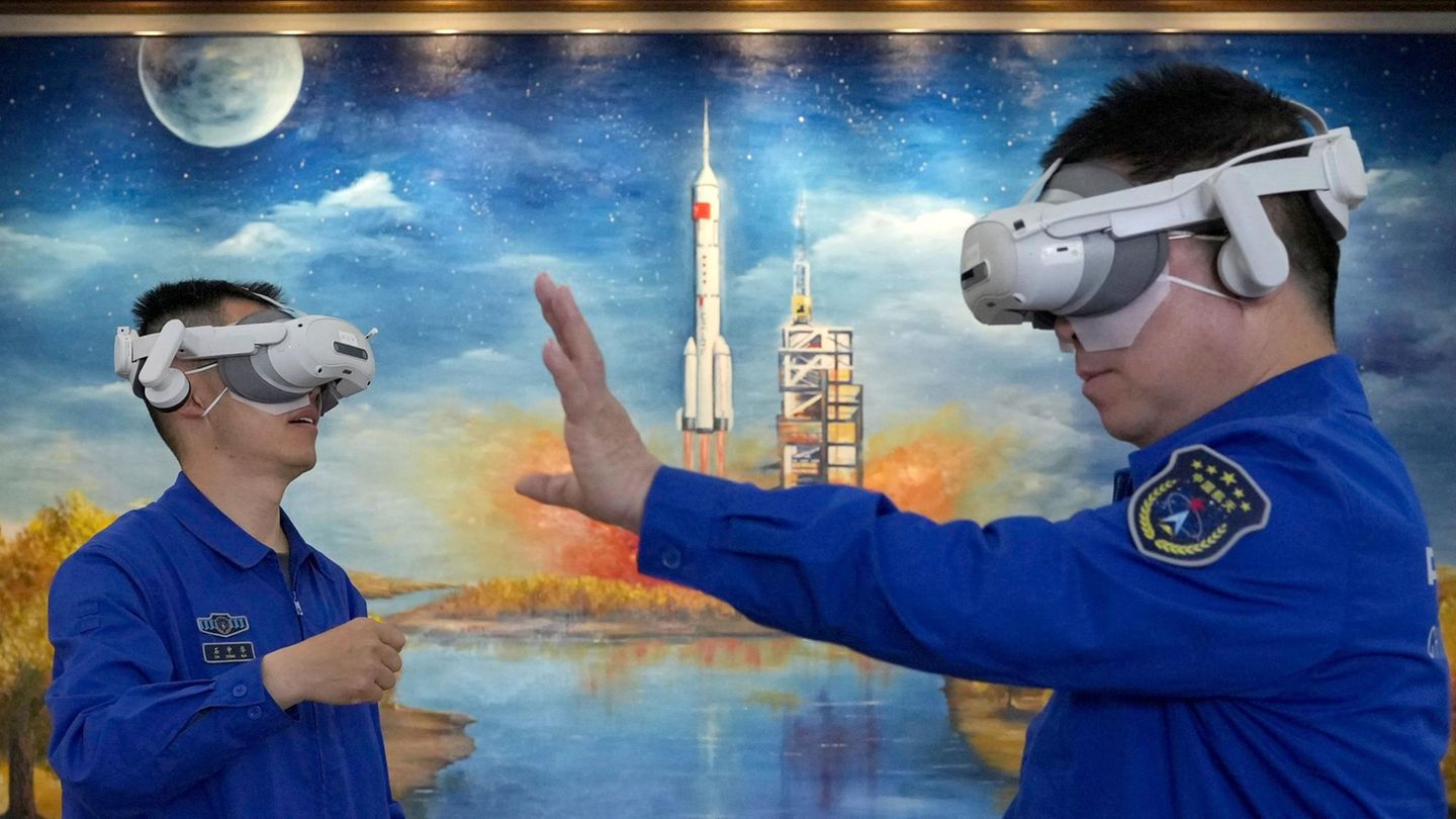 Zwei Personen schauen durch VR-Brillen, im Hintergrund ein Gemälde eines Raketenstarts