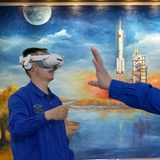 Zwei Personen schauen durch VR-Brillen, im Hintergrund ein Gemälde eines Raketenstarts