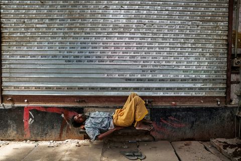 Mann schläft vor geschlossenem Laden in Varanasi in Uttar Pradesh