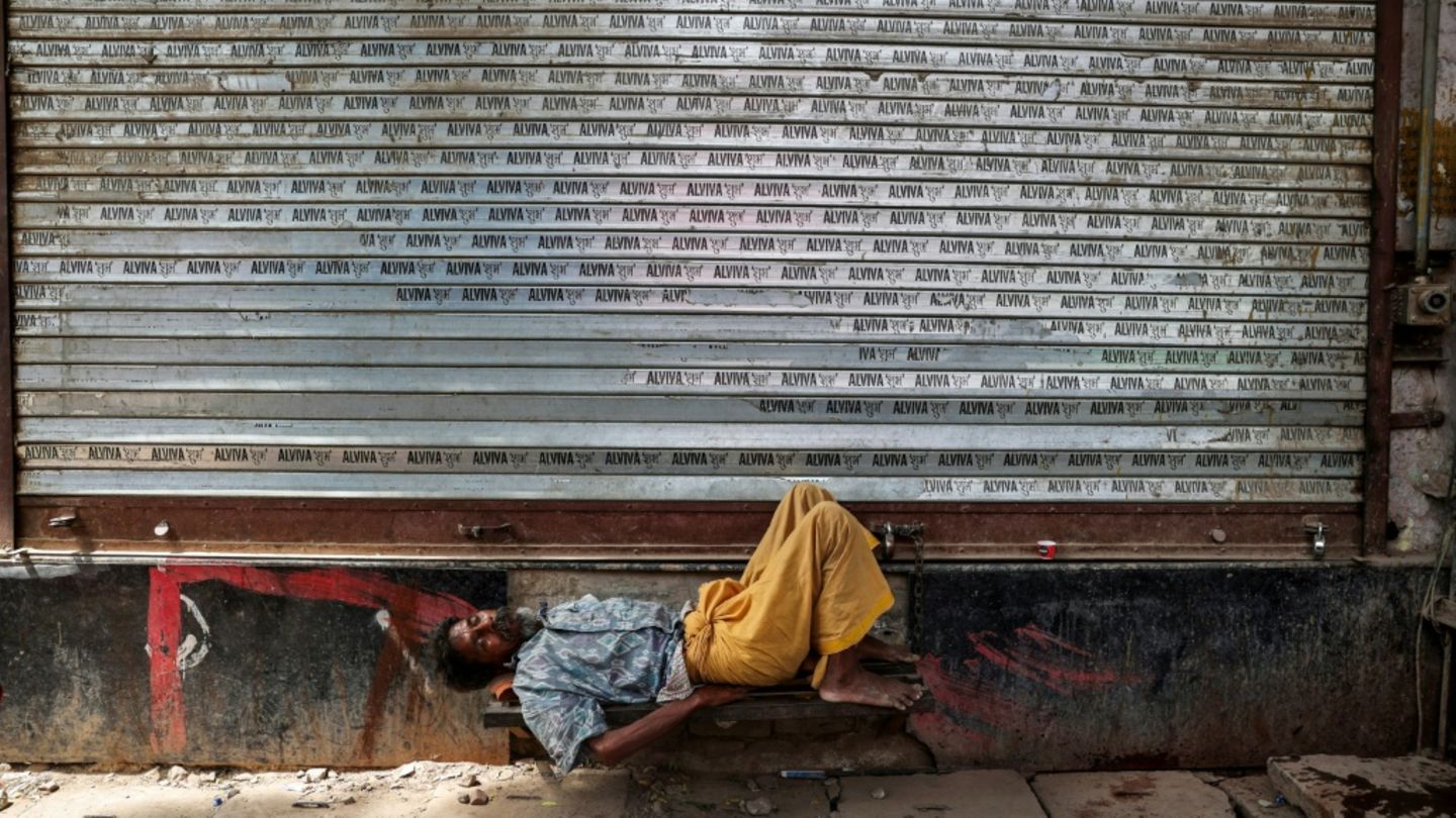 Mann schläft vor geschlossenem Laden in Varanasi in Uttar Pradesh