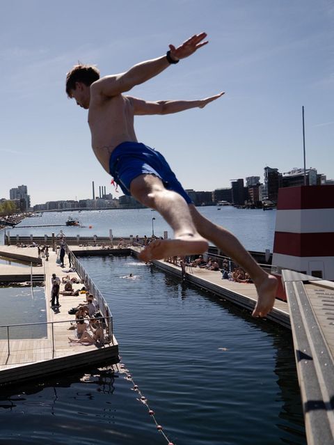 Eine Person springt ins Wasser: das ins Havnebadet Islands Brygge in Kopenhagen