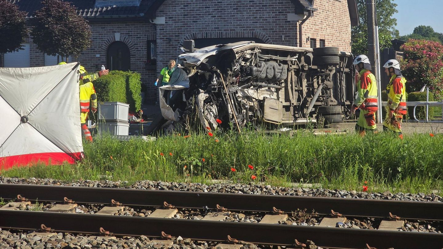 In Buggenhout, Belgien, liegt ein zerstörter Schulbus neben Bahngleisen auf der Seite