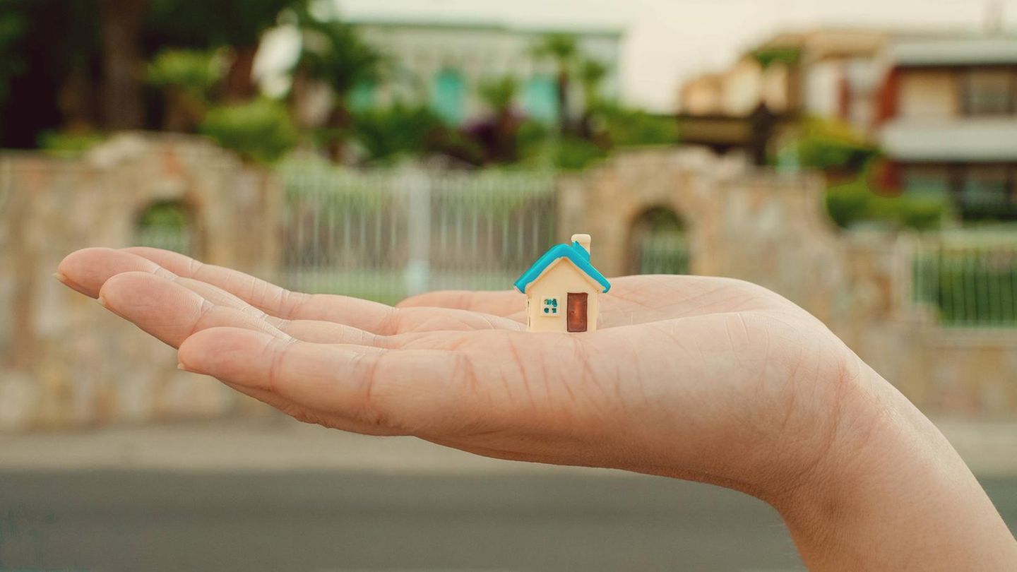 Hauskauf: Hand mit Miniaturhaus