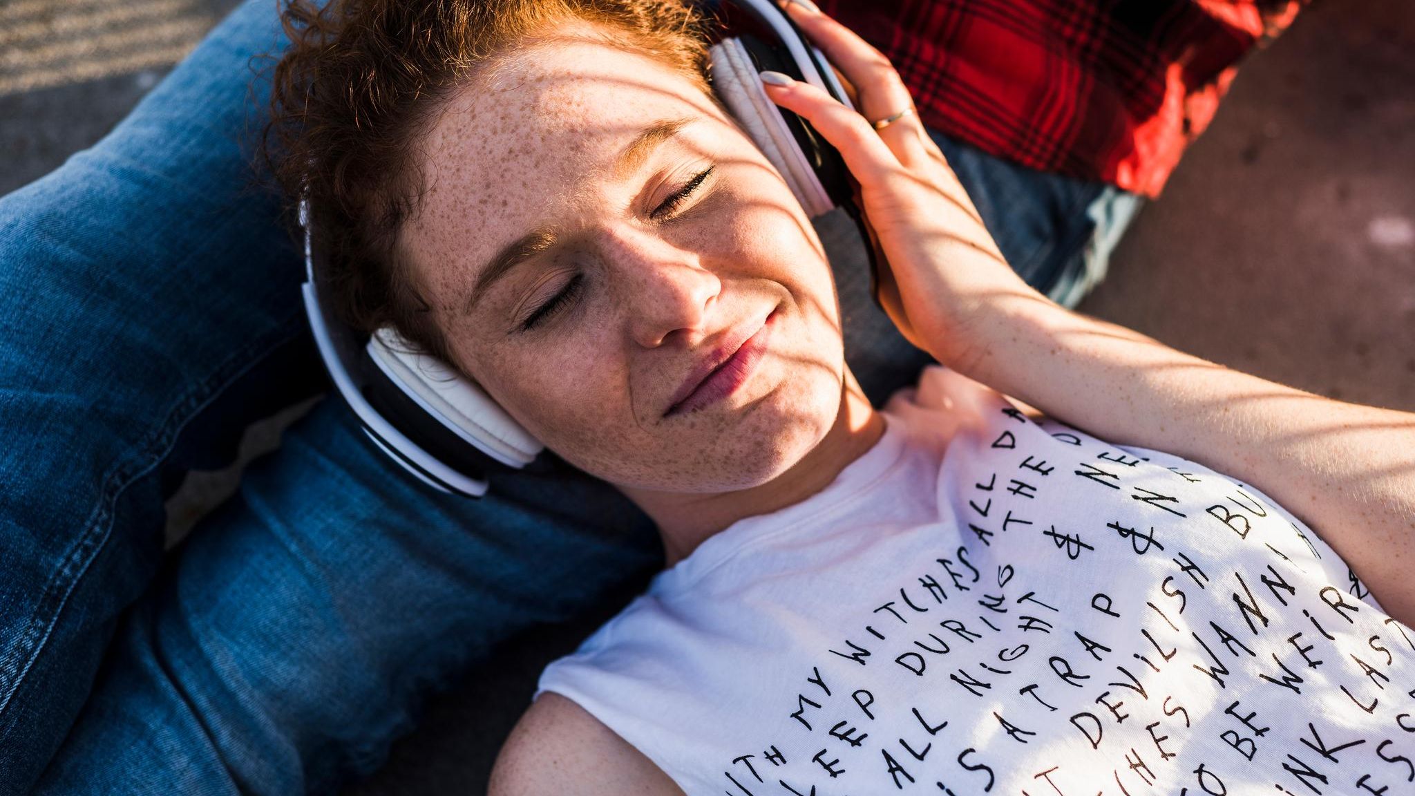 Eine junge Frau liegt auf dem Schoß ihres Freundes und hört Musik