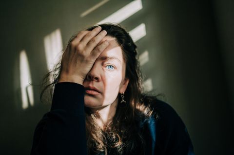 Eine Frau schaut erschöpft und abwesend in die Ferne
