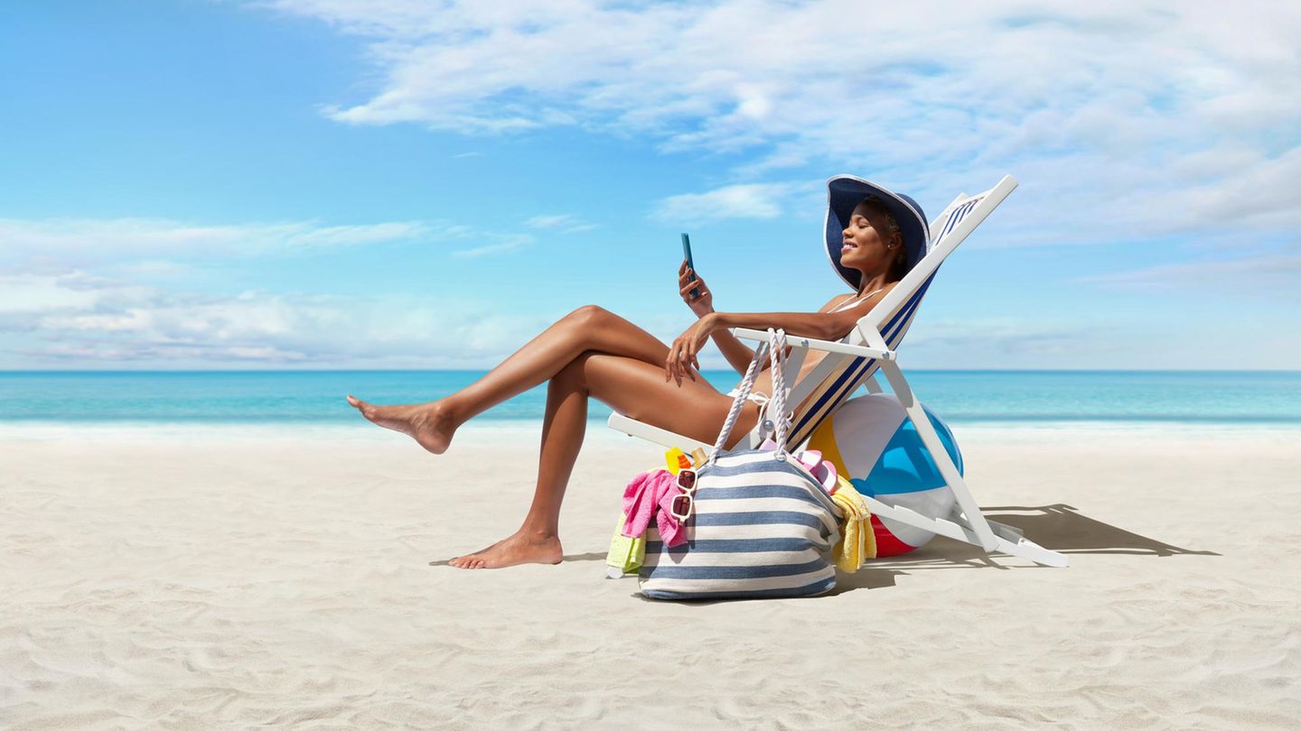 Glückliche Frau am Strand auf Strandliegestuhl