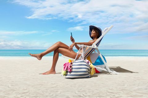 Glückliche Frau am Strand auf Strandliegestuhl