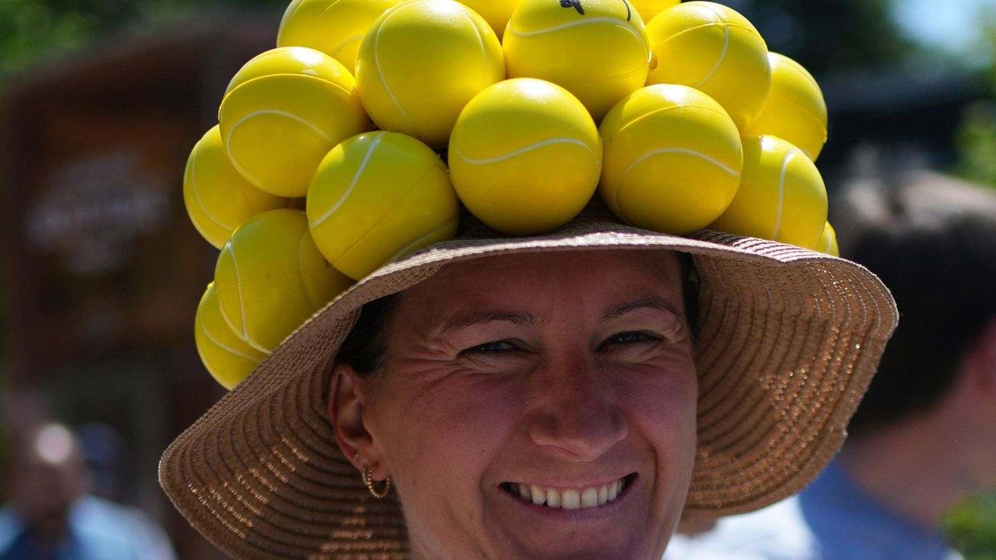 Eine Besucherin mit einem Hut, der mit Tennisbällen verziert ist