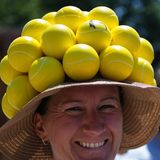 Eine Besucherin mit einem Hut, der mit Tennisbällen verziert ist