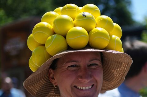 Eine Besucherin mit einem Hut, der mit Tennisbällen verziert ist