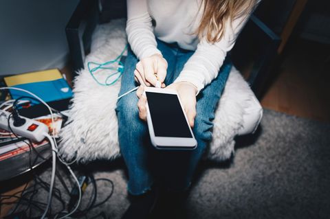 Ein Mädchen schließt ihr Smartphone an einem LAdekabel an