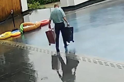 Mann läuft mit Koffern in den Pool