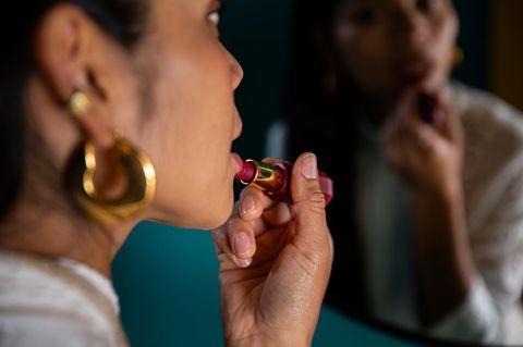 Frau, möglicherweise eine Escortdame, trägt Lippenstift auf
