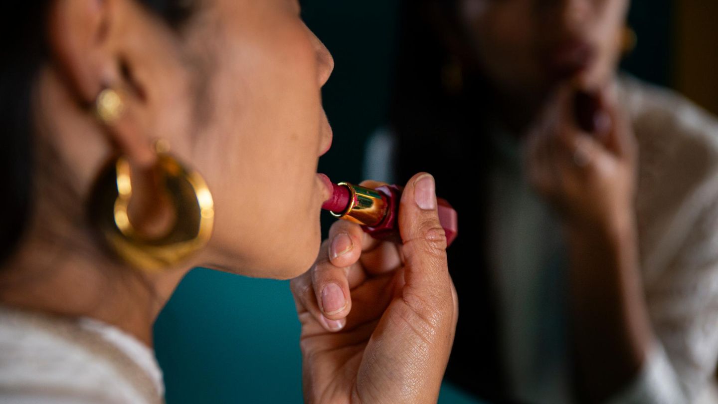Frau, möglicherweise eine Escortdame, trägt Lippenstift auf