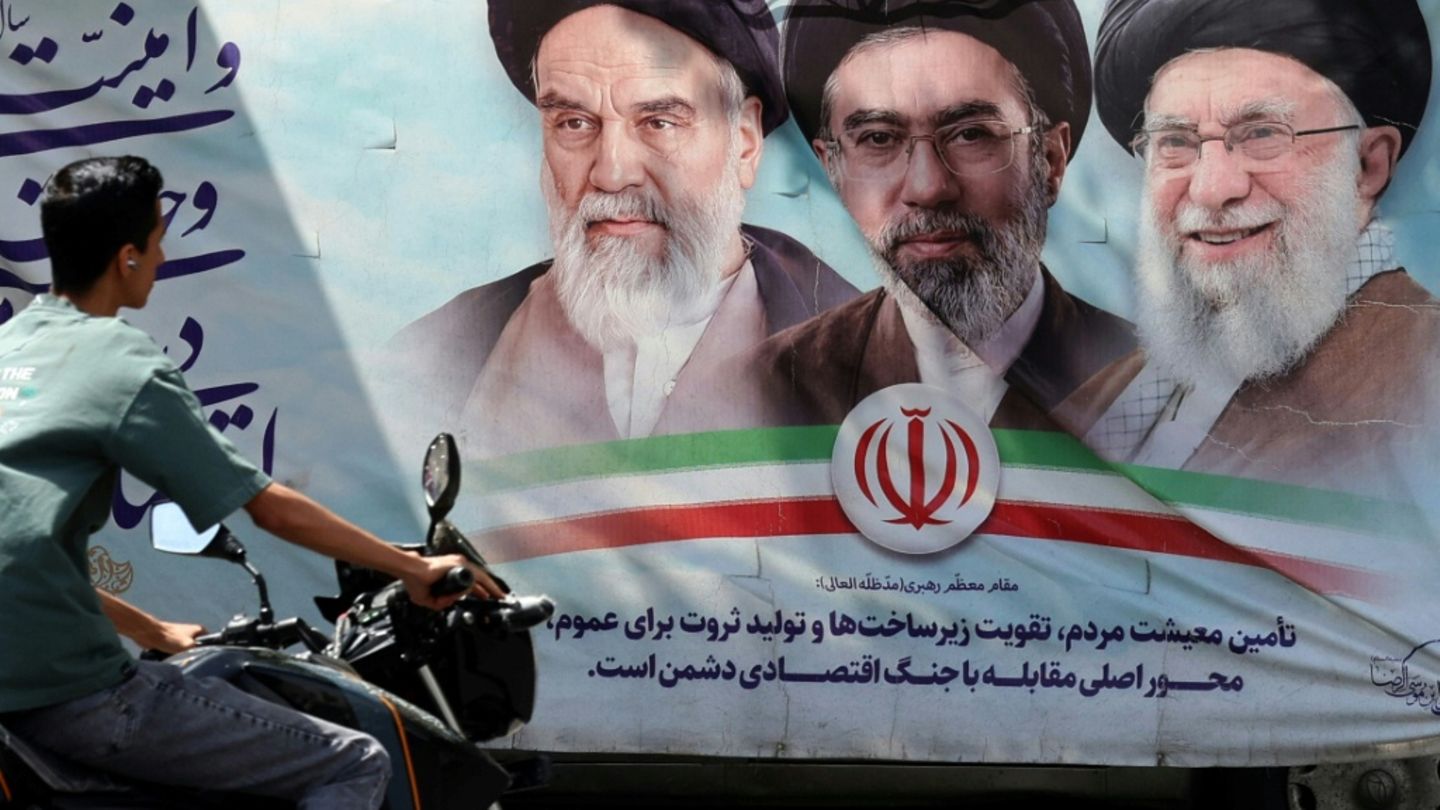 Iraner vor einem Propagandaplakat in Teheran