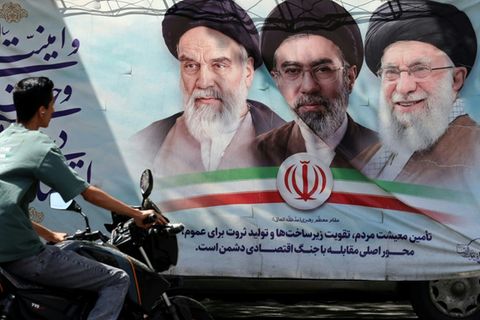 Iraner vor einem Propagandaplakat in Teheran