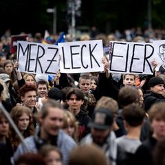 Schüler halten auf einer Demonstration Schilder mit den Worten „Merz leck Eier“ hoch.