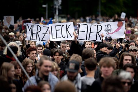 Schüler halten auf einer Demonstration Schilder mit den Worten „Merz leck Eier“ hoch.