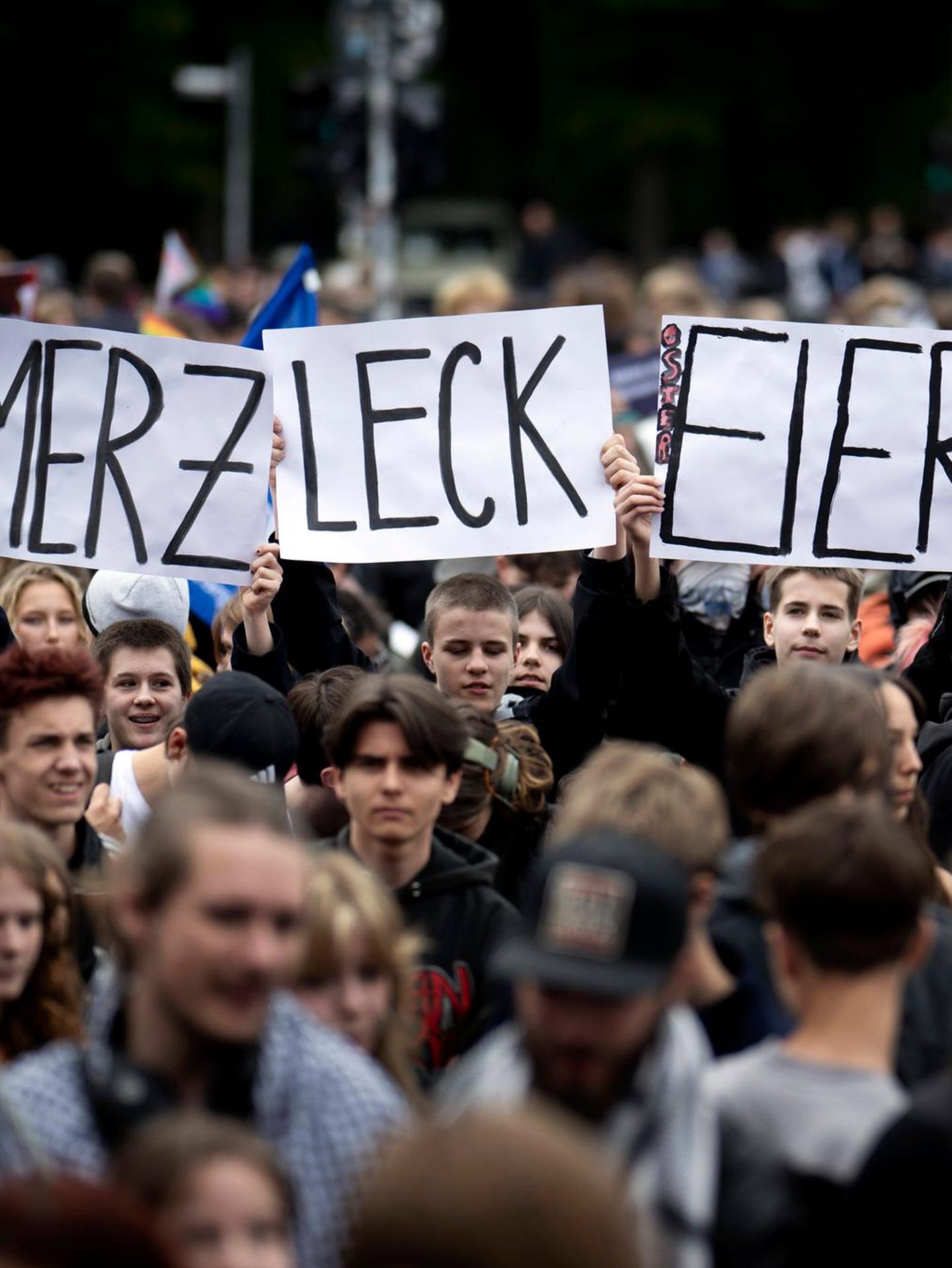 Schüler halten auf einer Demonstration Schilder mit den Worten „Merz leck Eier“ hoch.