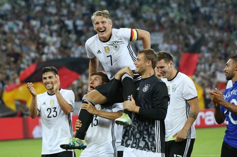Bastian Schweinsteiger wird nach seinem letzten Länderspiel gegen Finnland von Thomas Müller (l) und Manuel Neuer (r) auf Schult