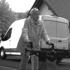 Ein Kastenwagen fährt an einer Frau mit Rollator vorbei