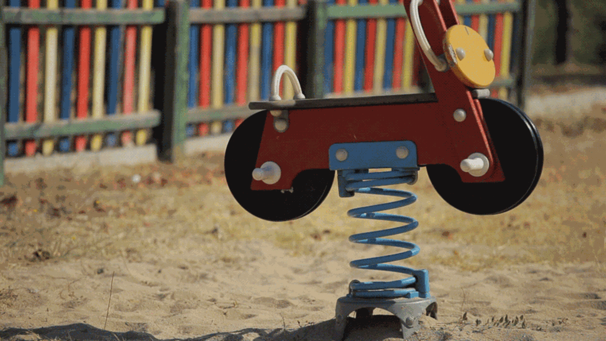 Ein Schaukelauto auf einem Spielplatz wackelt ohne Kind vor sich hin
