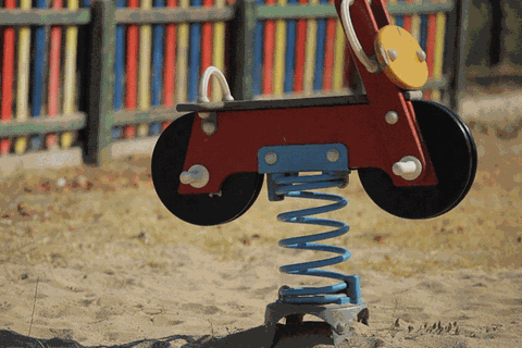 Ein Schaukelauto auf einem Spielplatz wackelt ohne Kind vor sich hin