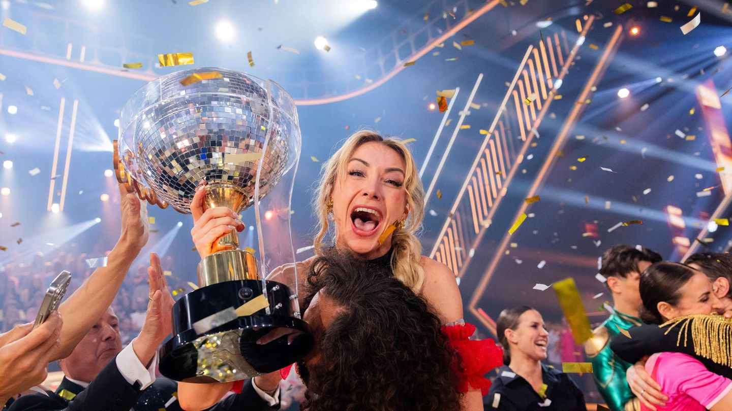 Die Siegerin jubelt und hält einen Disco-Pokal in den Händen, ihr Tanzpartner hebt sie hoch