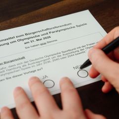 Eine Hand mit einem Kugelschreiber über einem Abstimmungszettel zur Olympia-Bewerbung von Hamburg