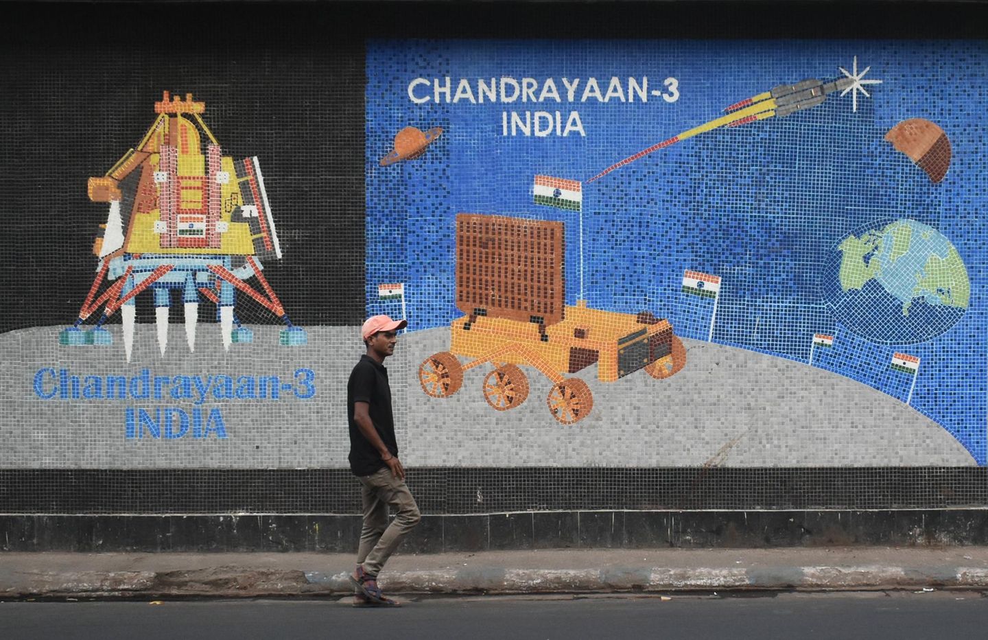 Ein Mann geht an einem Wandmosaik vorbei, auf dem das indische Raumfahrtprogramm zu sehen ist