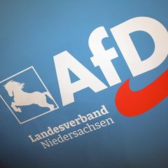 Das Logo des AfD Landesverband Niedersachsen hängt an einer Wand im Saal
