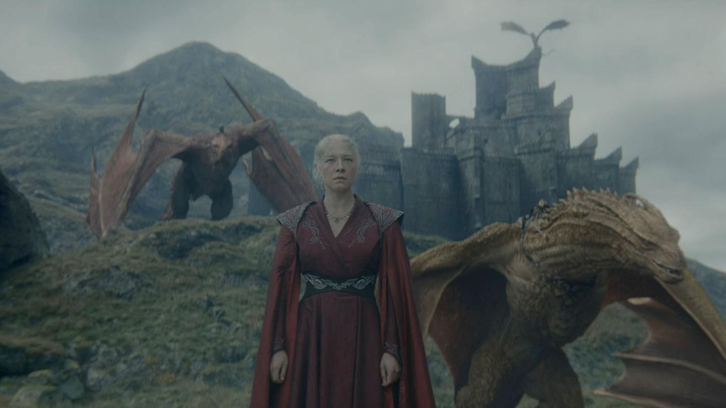 Rhaenyra Targaryen steht mit zwei Drachen an ihrer Seite vor einer Burg