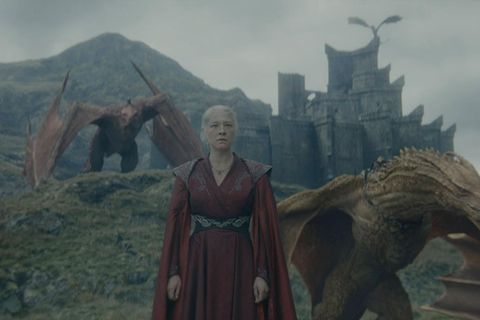 Rhaenyra Targaryen steht mit zwei Drachen an ihrer Seite vor einer Burg