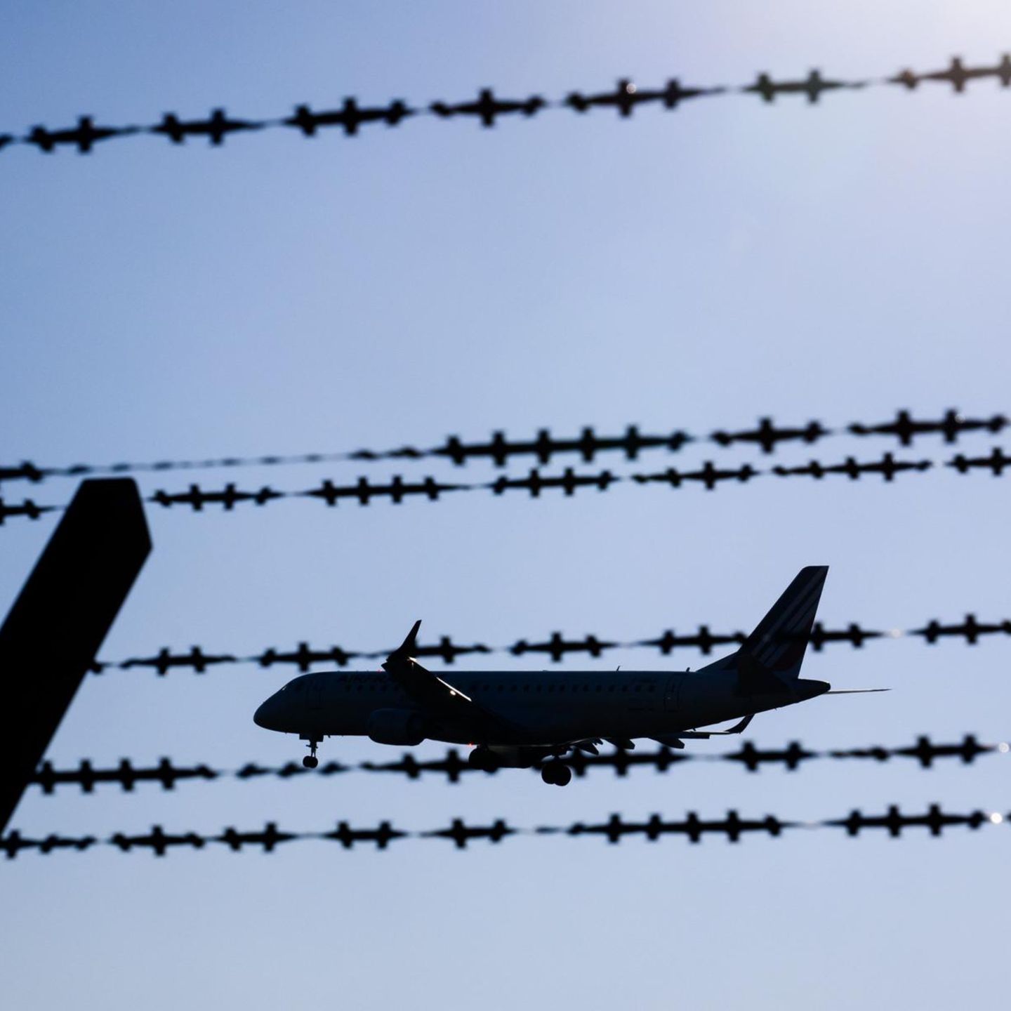 Ein Flugzeug fliegt hinter Stacheldraht am Flughafen Hannover