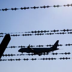 Ein Flugzeug fliegt hinter Stacheldraht am Flughafen Hannover