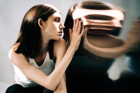 Eine Frau betrachtet ihr verzerrtes Spiegelbild