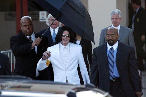 Michael Jackson läuft unter einem Regenschirm und lächelt in die Kamera
