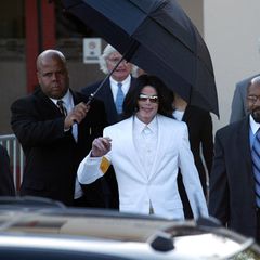 Michael Jackson läuft unter einem Regenschirm und lächelt in die Kamera