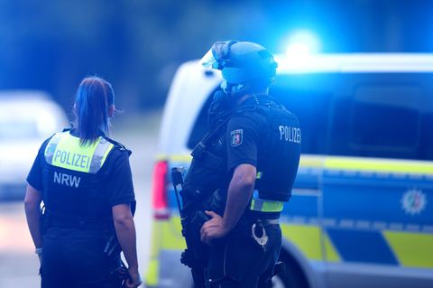 Zwei Polizisten stehen vor einem Polizeifahrzeug (Symbolfoto)