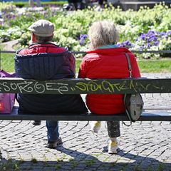 Ein äteres Ehepaar sitzt auf einer Bank