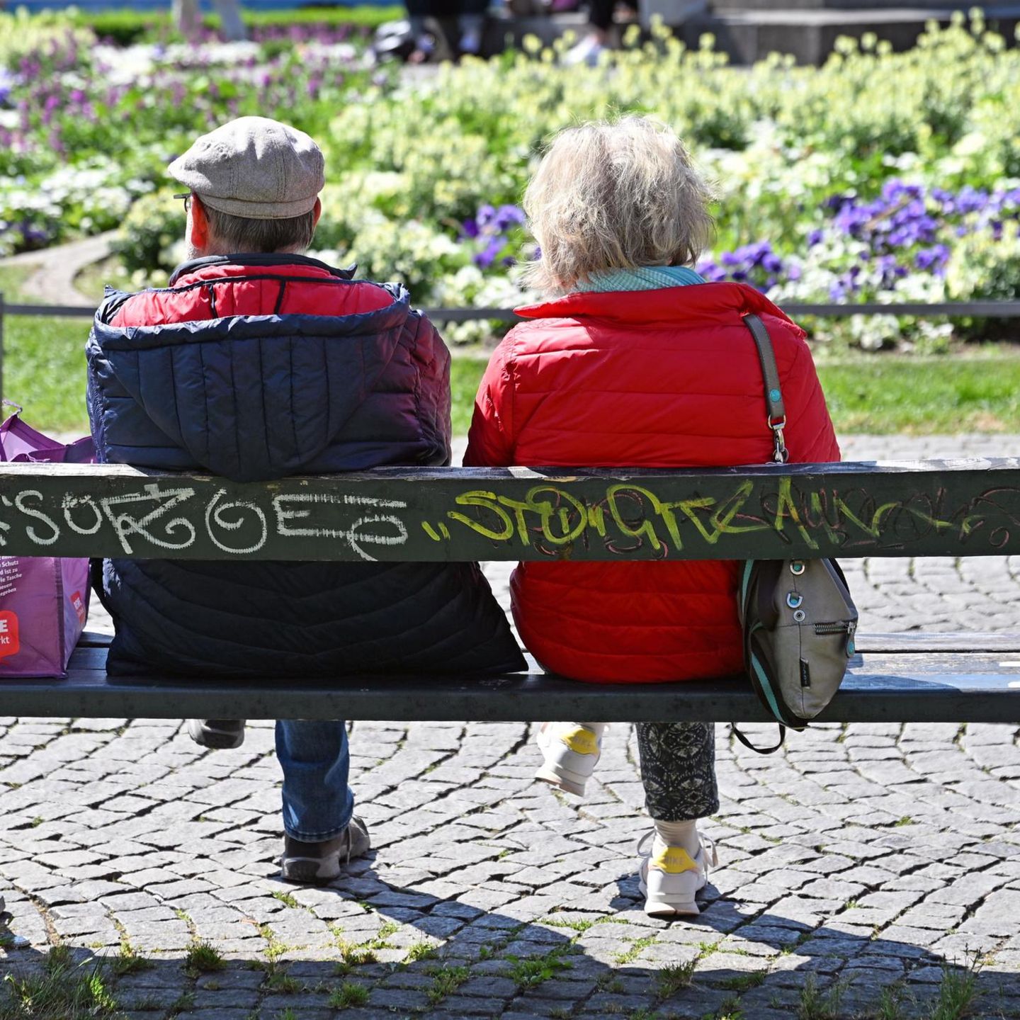 Ein äteres Ehepaar sitzt auf einer Bank