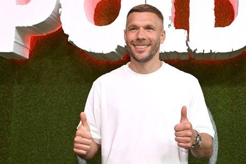 Lukas Podolski regelt seine Geschäfte locker am Handy.