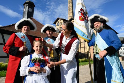 Vor der historischen Saline geben Hauptmann Uwe Frosch (l-r), Hallorenbraut Finja, Tobias Heinicke, Erster und Regierender Vorst