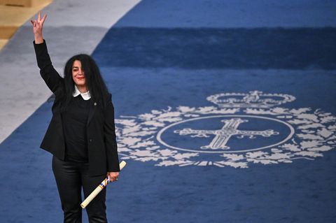 Marjane Satrapi reckt den Arm in die Luft und macht ein Peace-Zeichen